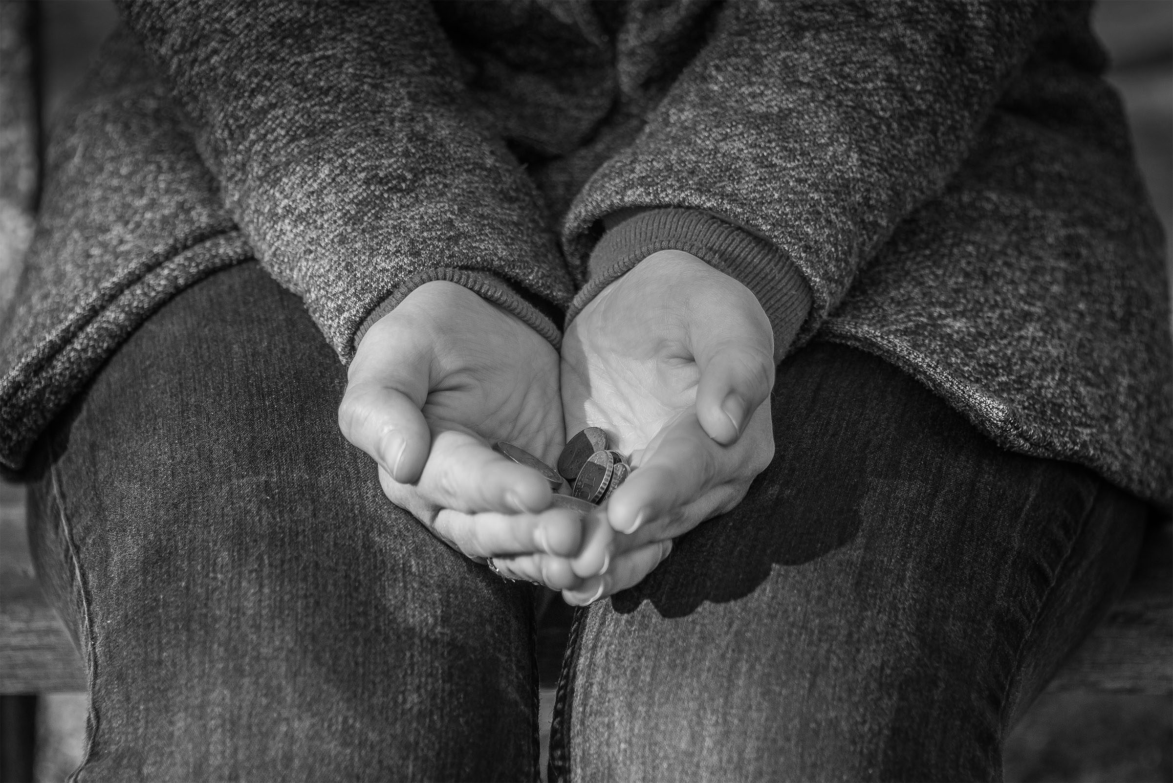 Twee open handen die een muntje vasthouden, in zwart-wit