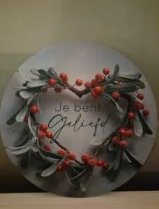 Decoratieve tegel met een hartvormige krans en de tekst ‘Je bent geliefd’