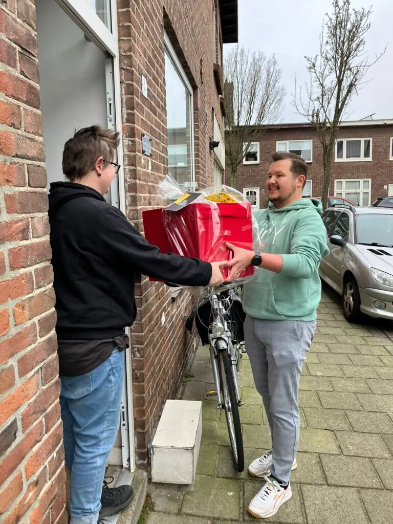 Een vrijwilliger overhandigt een kerstpakket aan de deur