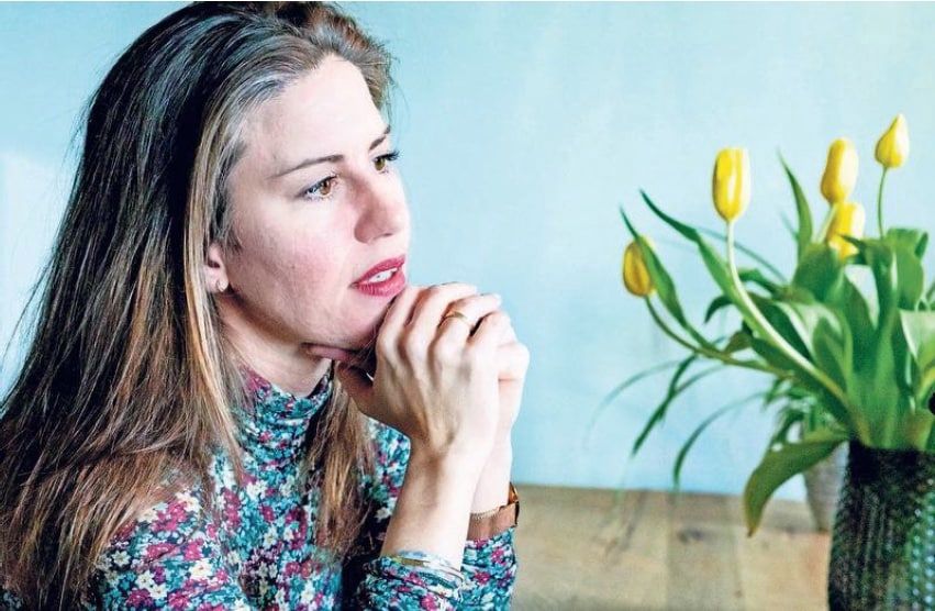 Portret van Stephanie-Joy Eerhart aan tafel, met tulpen op de achtergrond